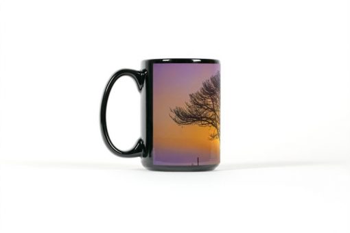 Left view of black mug with a tree silhouetted by a sunset